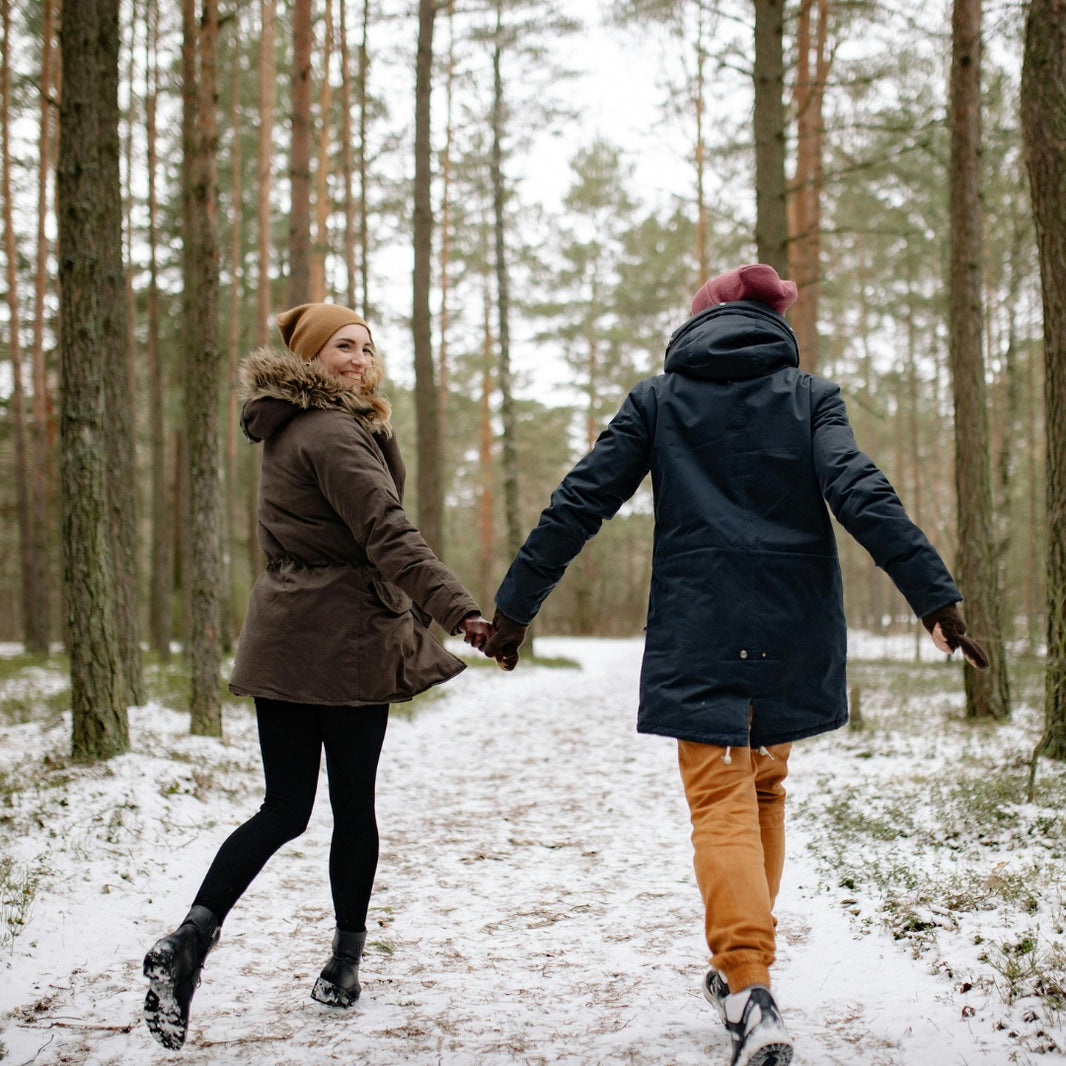 Two people holding hands in a snowy forest