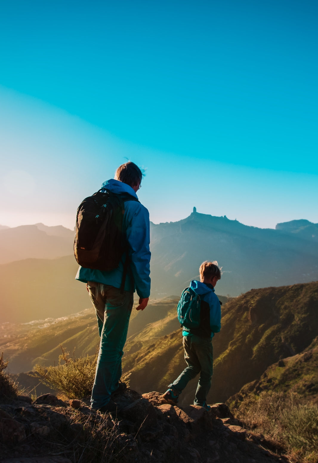 Two people standing on a mountain top with a clear blue sky